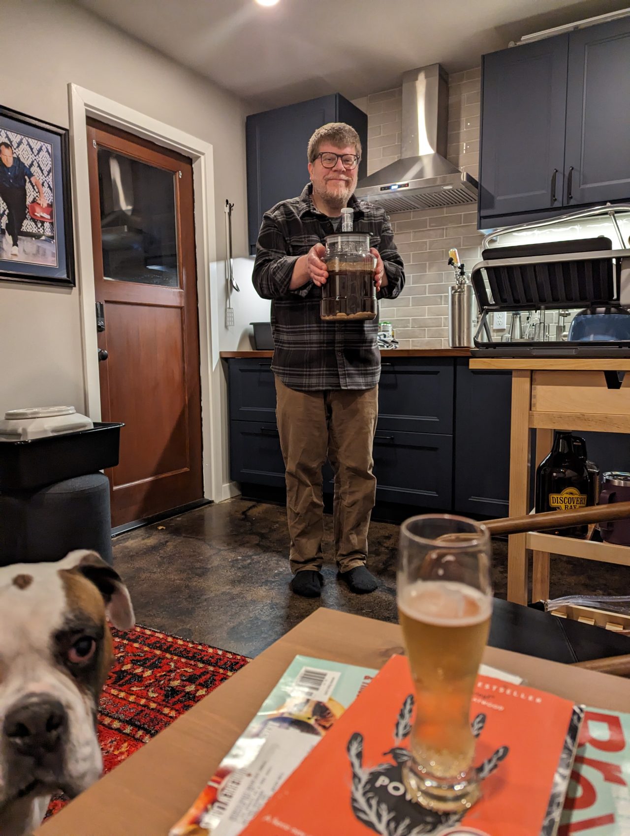 Photo of me holding a one-gallon fermenter containing at batch of Bourbon Porter, and my dog Petey in the lower-left corner looking concernedly at the camera