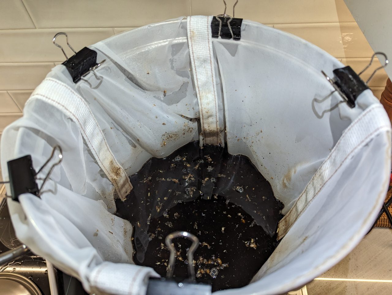 Photo looking down into an electric brewing kettle with a mesh bag clipped to the kettle and grains and water inside the kettle for an Irish Stout
