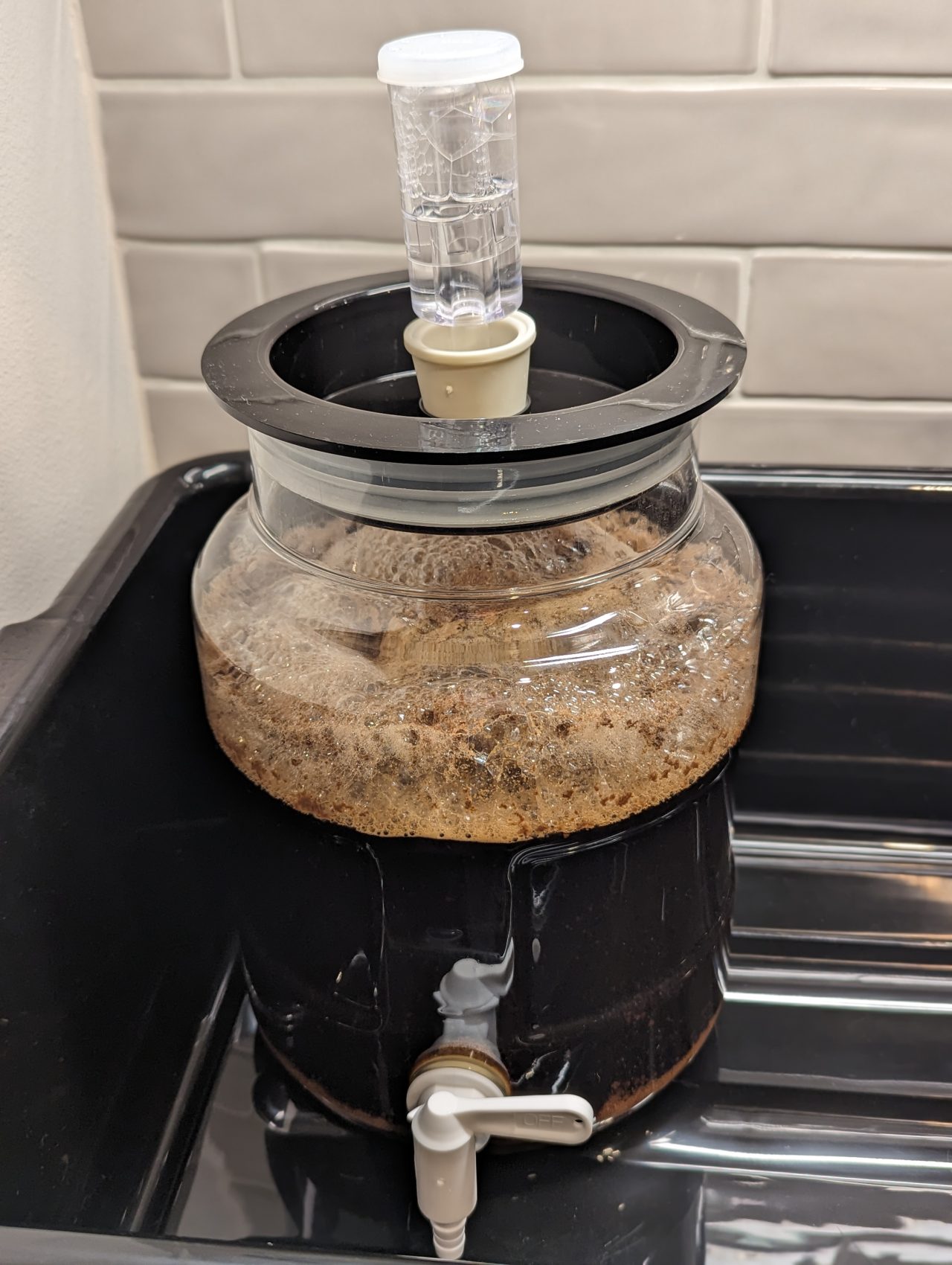 Photo of a batch of Stout beer in a one-gallon fermenter with foam on top