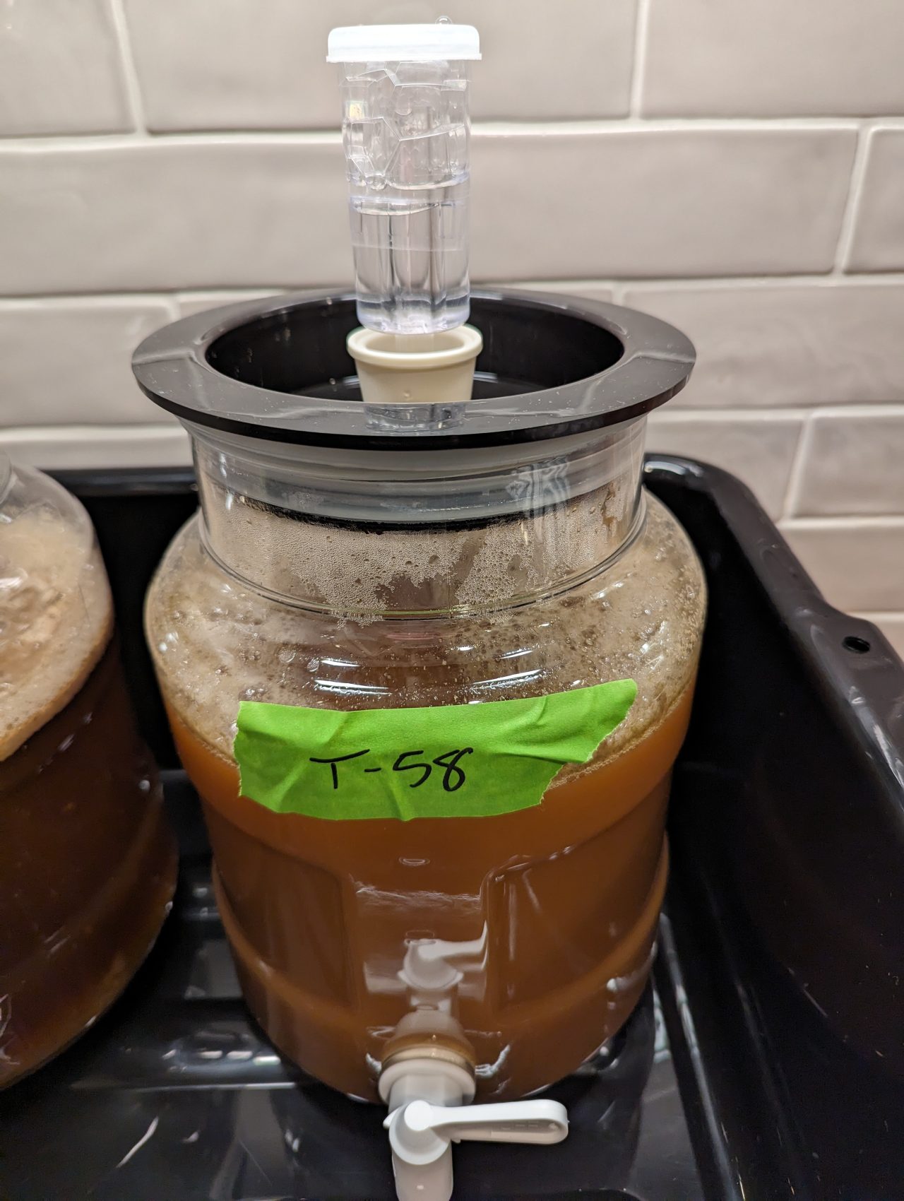 Photo of beer fermenting in a plastic fermenter with the label "T-58" on green masking tape