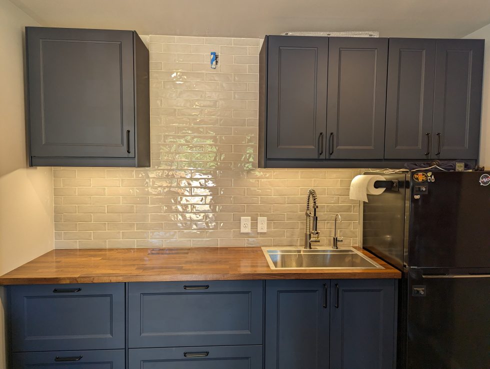Photo of grey/beige subway tiles on a wall with navy blue cabinets