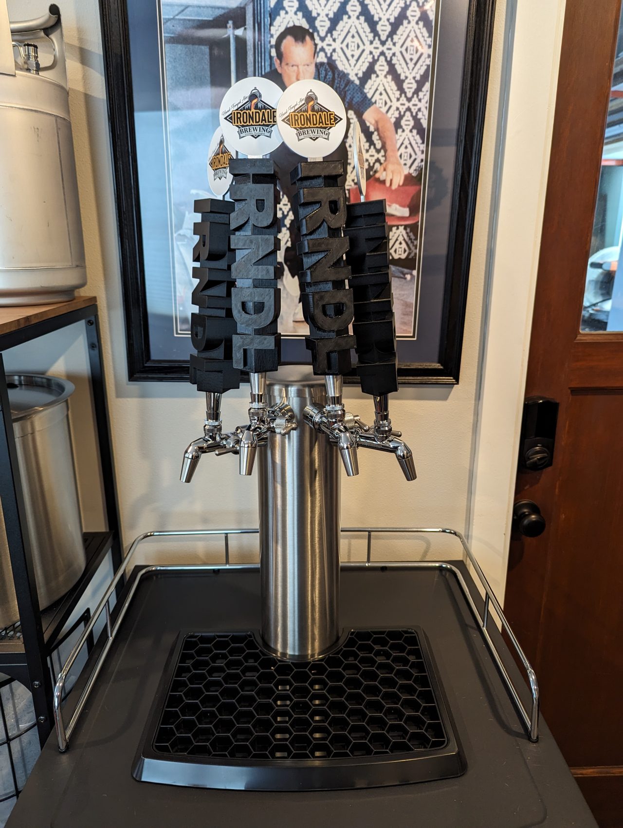 Photo of a four-tap stainless steel beer tower on a kegerator with Irondale Brewing tap handles