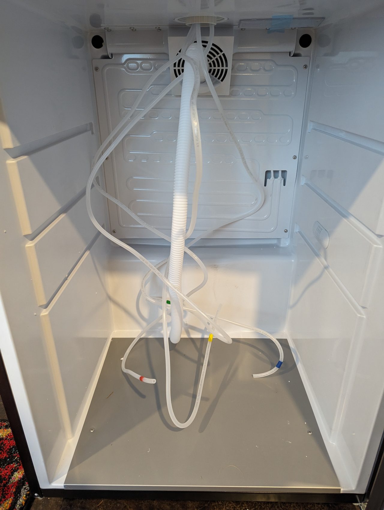Photo of four beer lines marked with colored masking tape draped on the inside of a kegerator