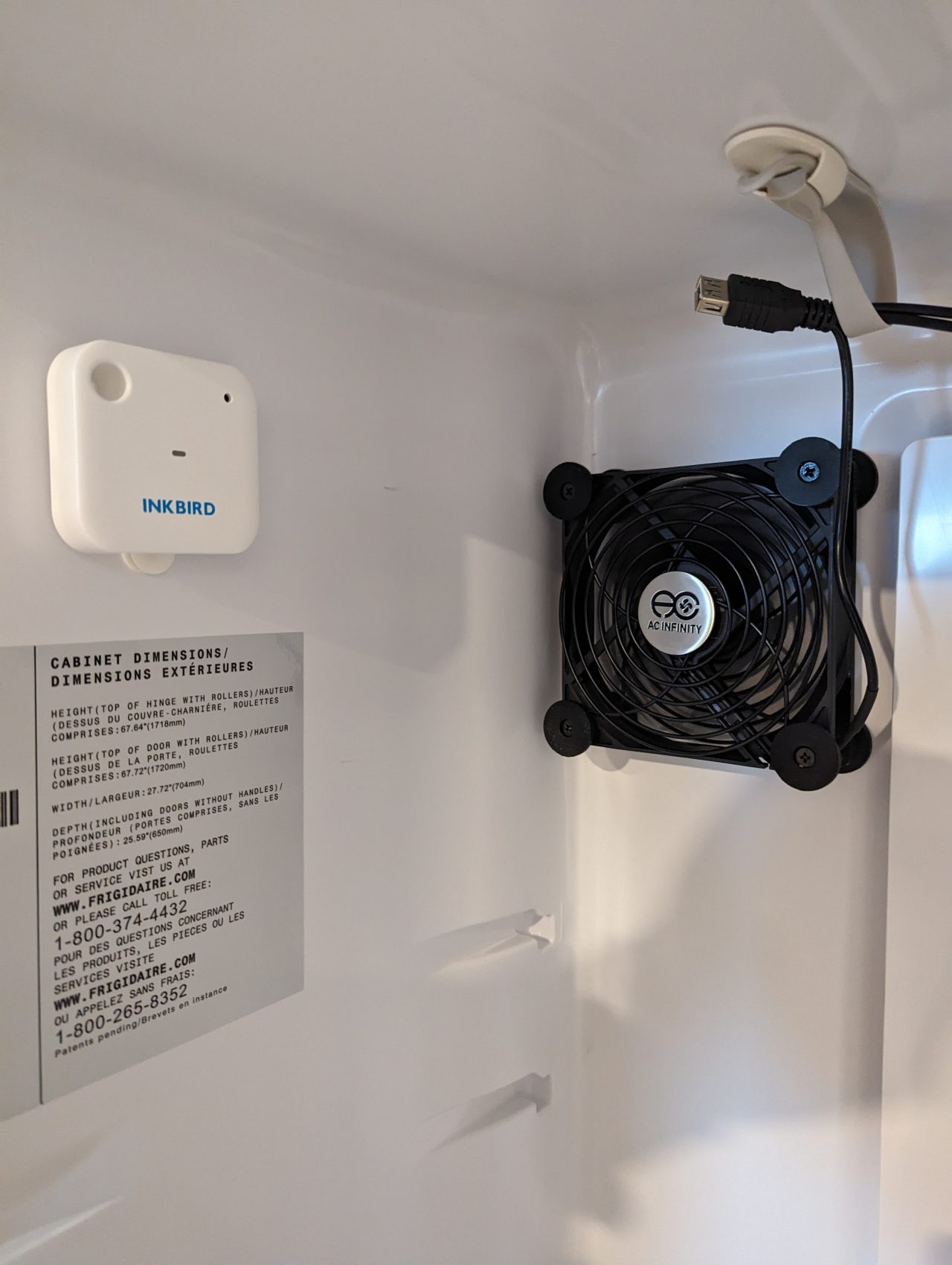 Photo of a small Inkbird temperature and humidity sensor mounted to the inside wall of an upright freezer