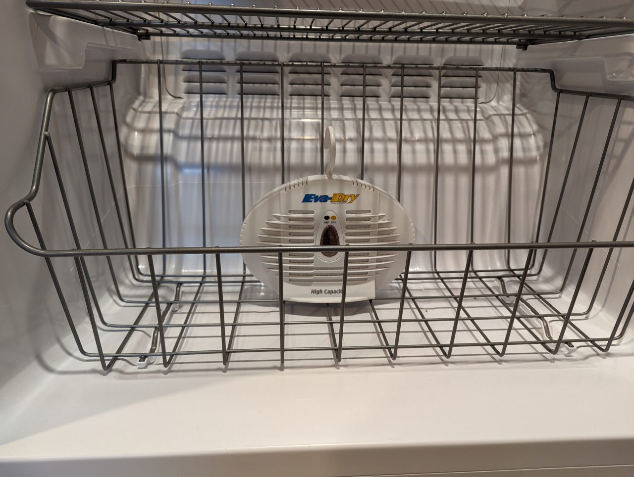 Photo of an Eva-Dry 500 dehumidifier in the bottom basket of an upright freezer